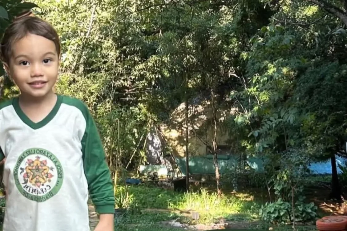 Aluno da Escola Curumim de uniforme na área verde da escola